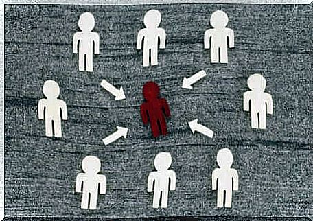 Group of white human silhouettes surrounding a red silhouette. 