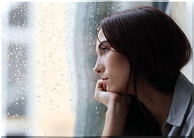 Woman watching the rain through the window.