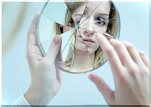 woman looking at herself in a broken mirror