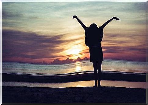 Woman-stretching-her-arms-in front-of-sunset